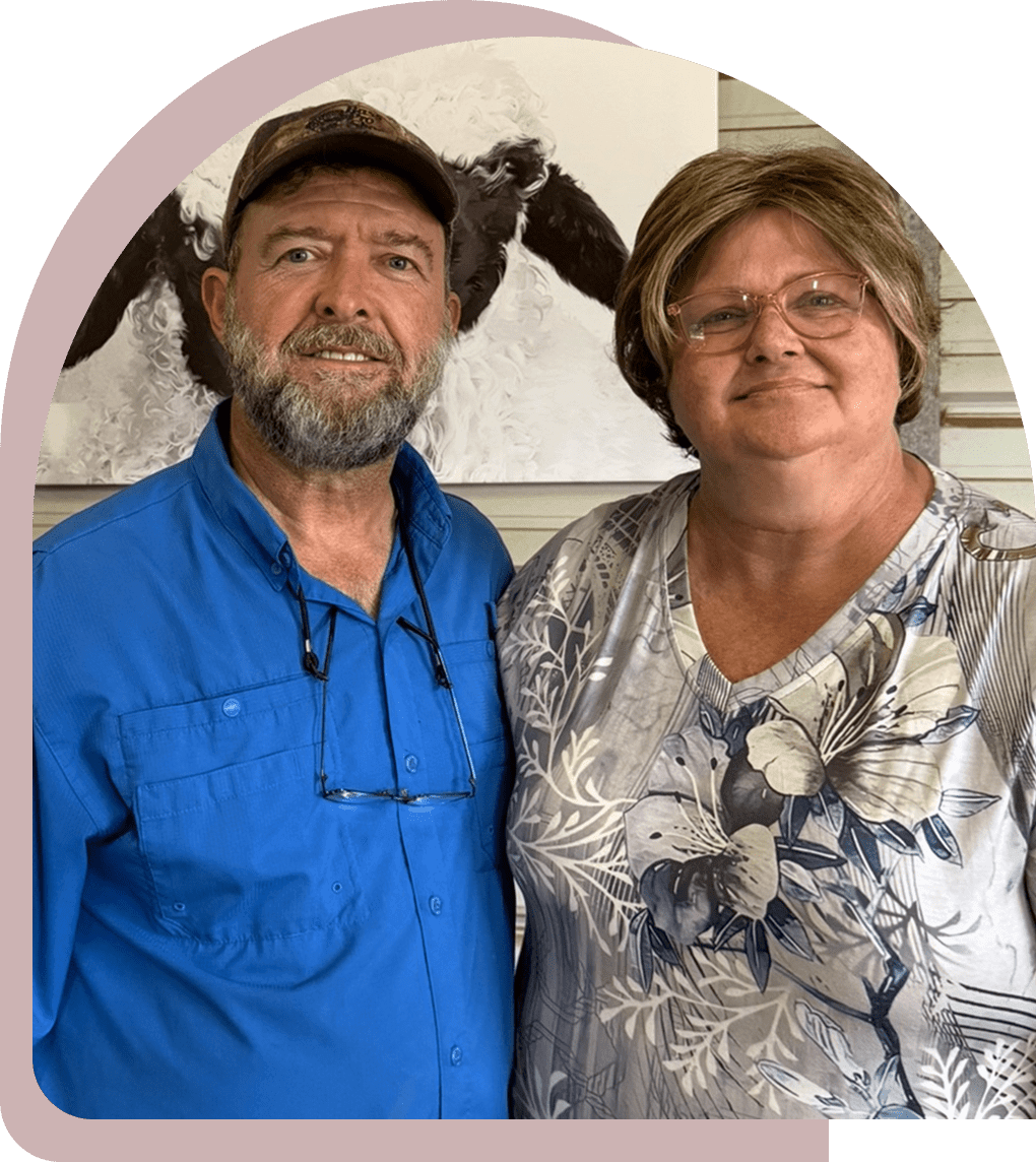 A man and woman standing side by side, smiling indoors.