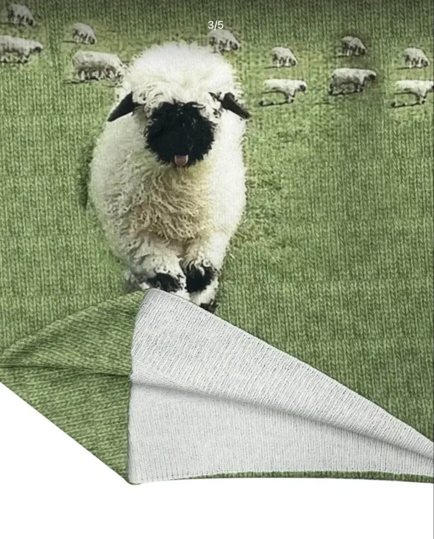 A green towel with a sheep's face design, partially folded.